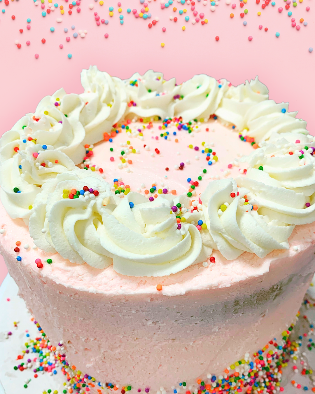 Pink and white birthday cake with sprinkles